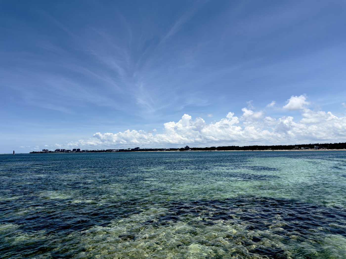 Turquoise reef flats of the Indian Ocean under a streaked blue sky at Nyali Beach