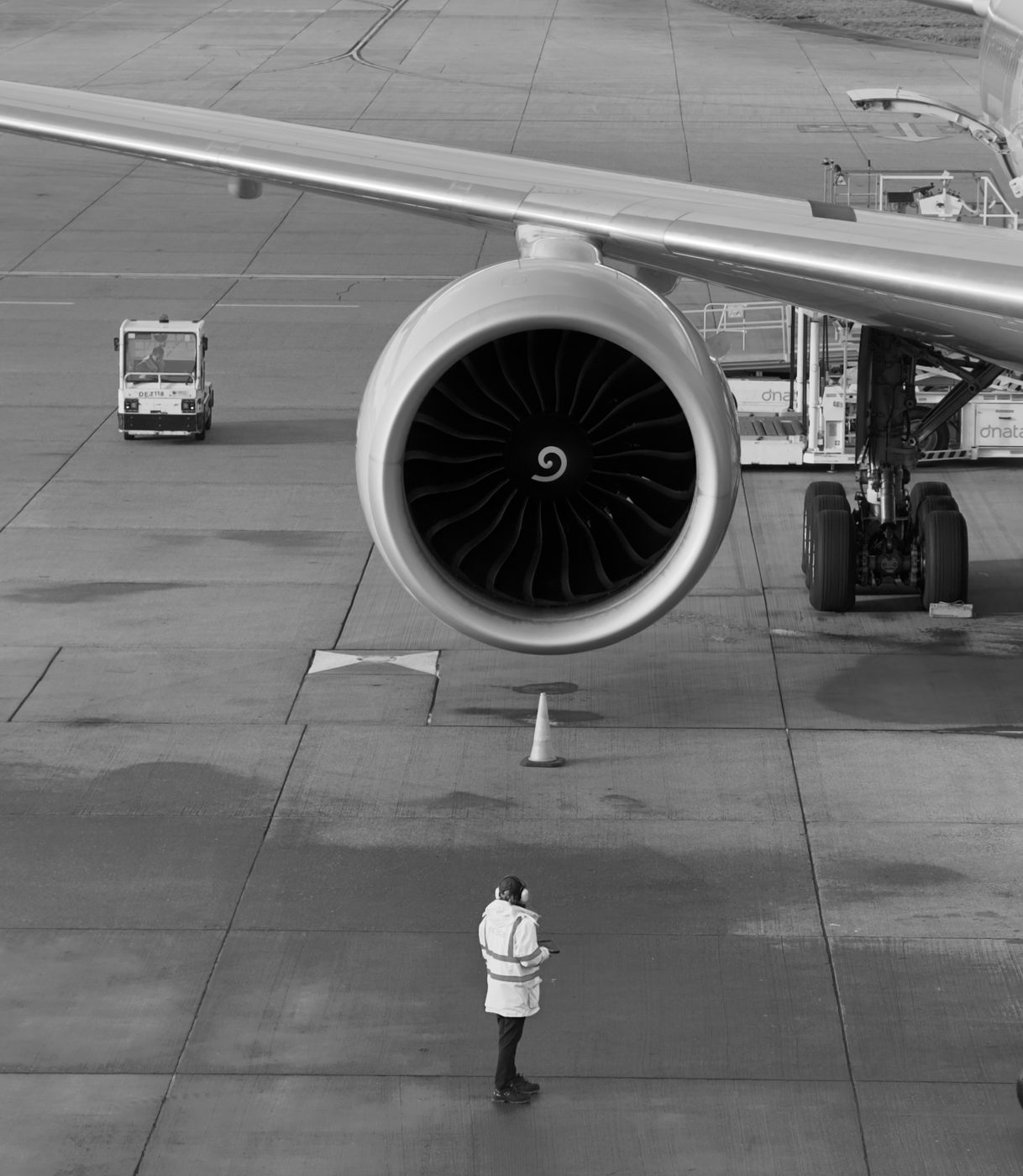 An aircraft engine and ground crew member on the tarmac at Doha, in black and white