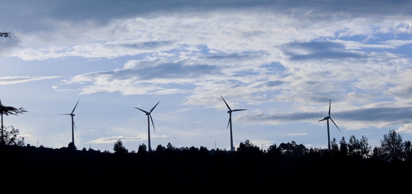 Wind turbines and telecom masts silhouetted along the Ngong Hills ridge at dusk