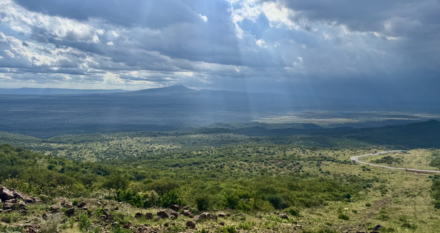 Sun rays breaking through clouds over the green Rift Valley floor seen from Mount Suswa