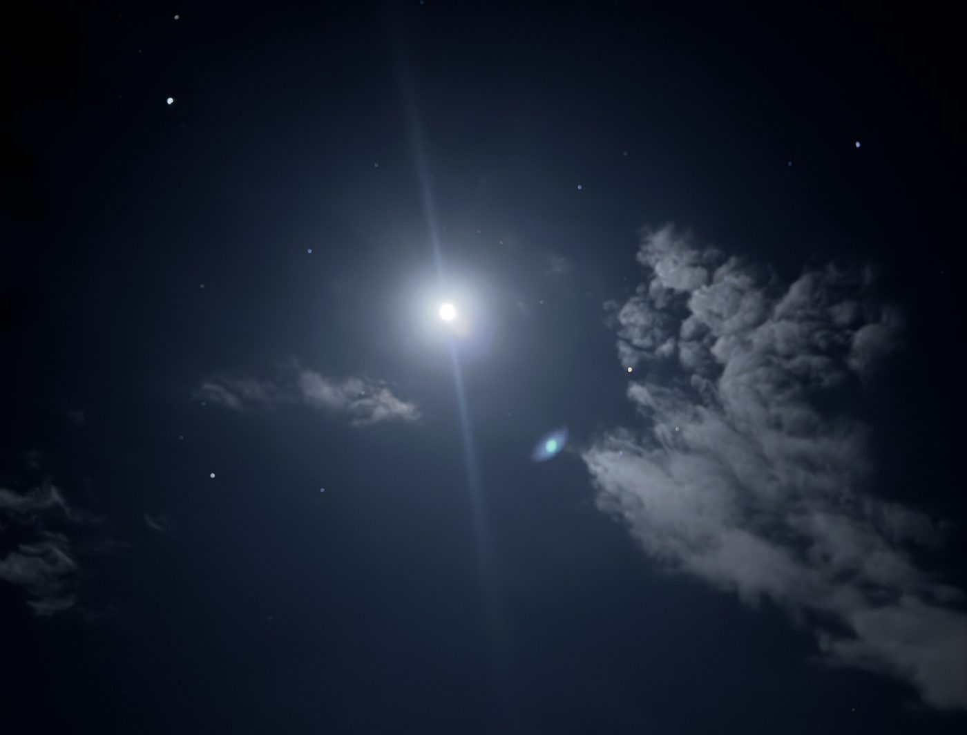 A bright moon and stars in a dark night sky beside a lone cloud
